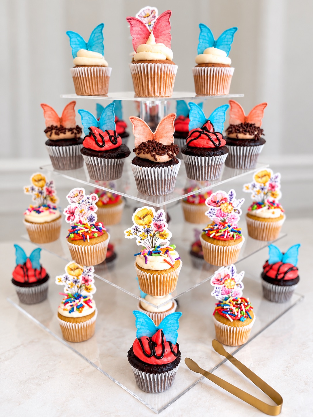 Tiered display of mini cupcakes with colorful butterfly decorations