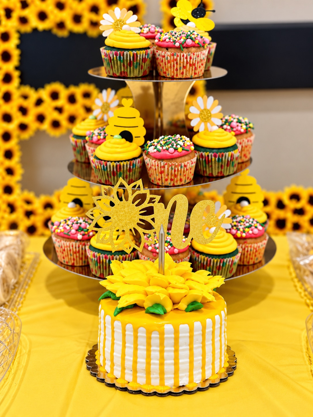 Sunflower-themed cake and mini cupcake display